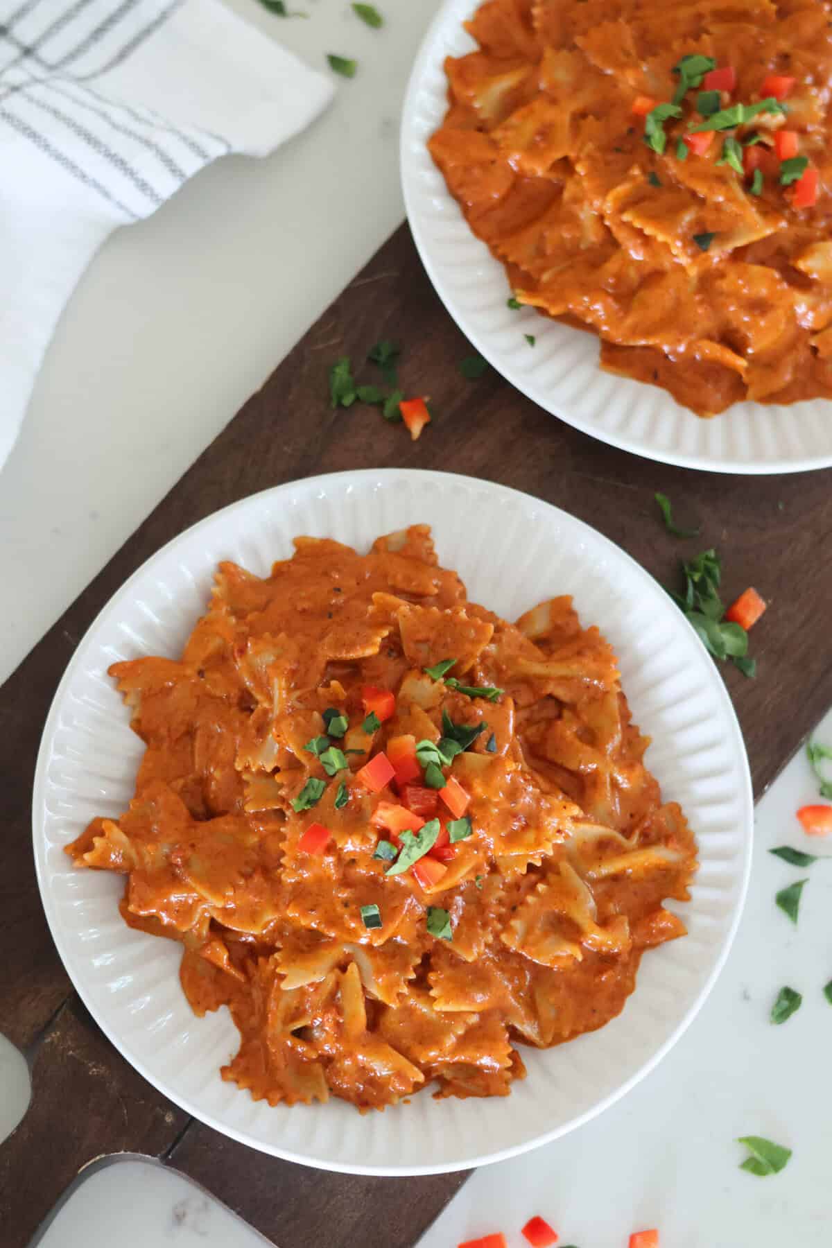 Two white plates of Quick And Easy Chorizo Pasta on a cutting board.