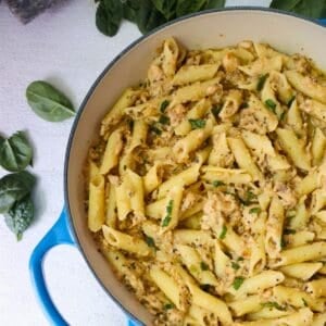 A pan of Canned Salmon with Pasta on a white counter with spinach.