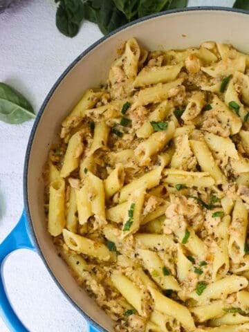 A pan of Canned Salmon with Pasta on a white counter with spinach.