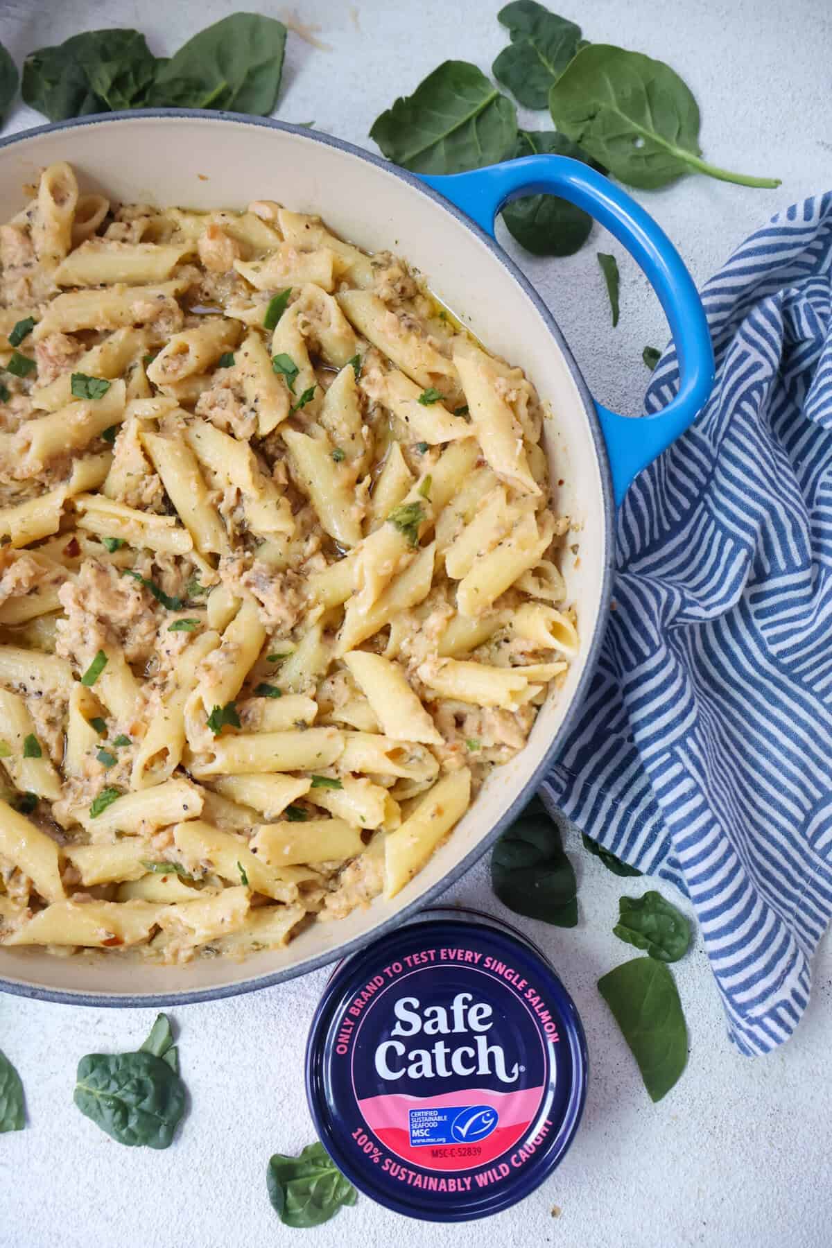 A pan of Canned Salmon with Pasta on a white counter with spinach.