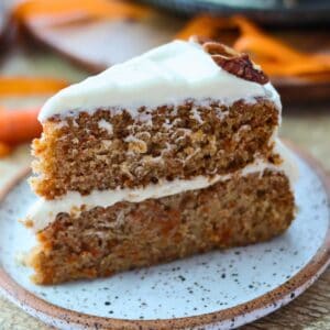 A slice of Dairy Free Carrot Cake on a white plate with carrot decorations.