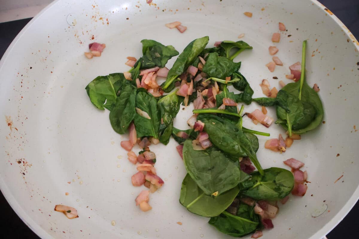 Spinach and red onion and garlic in a pan starting to cook.