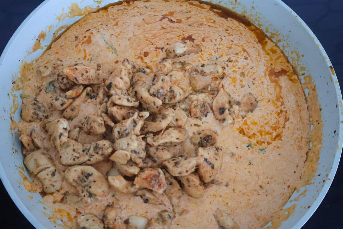 Pesto and Sun Dried Tomato sauce with chicken in a pan.