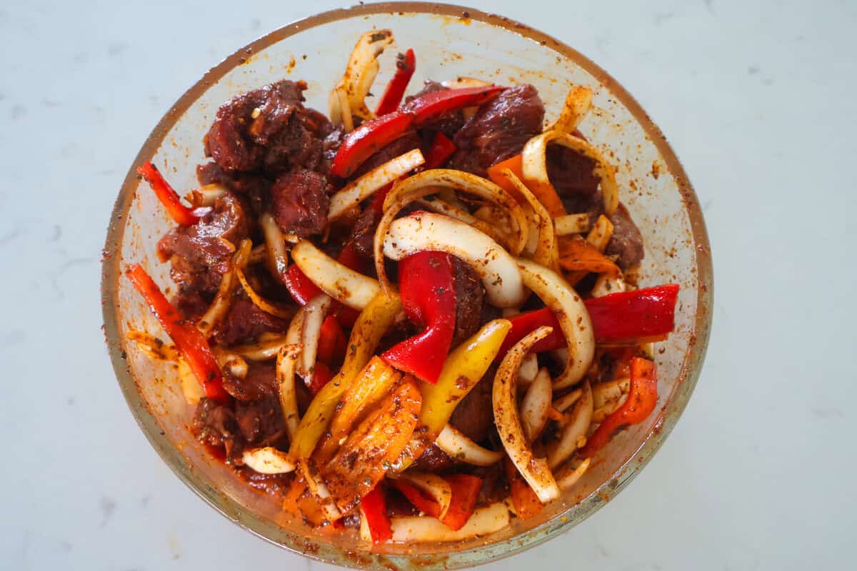 Steak fajitas marinating in a bowl.