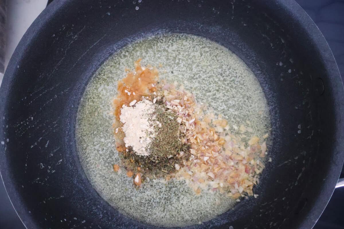 Seasonings for Alfredo sauce in a black pan on the stove.