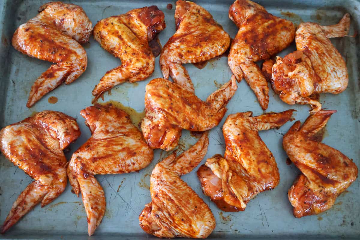 11 raw chicken wings laid out on a baking tray about to go in the oven.