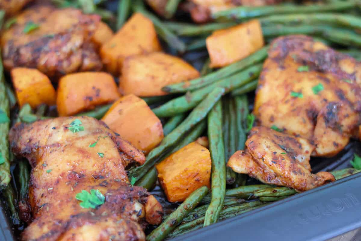A sheet pan of chicken thighs, green beans and sweet potatoes.