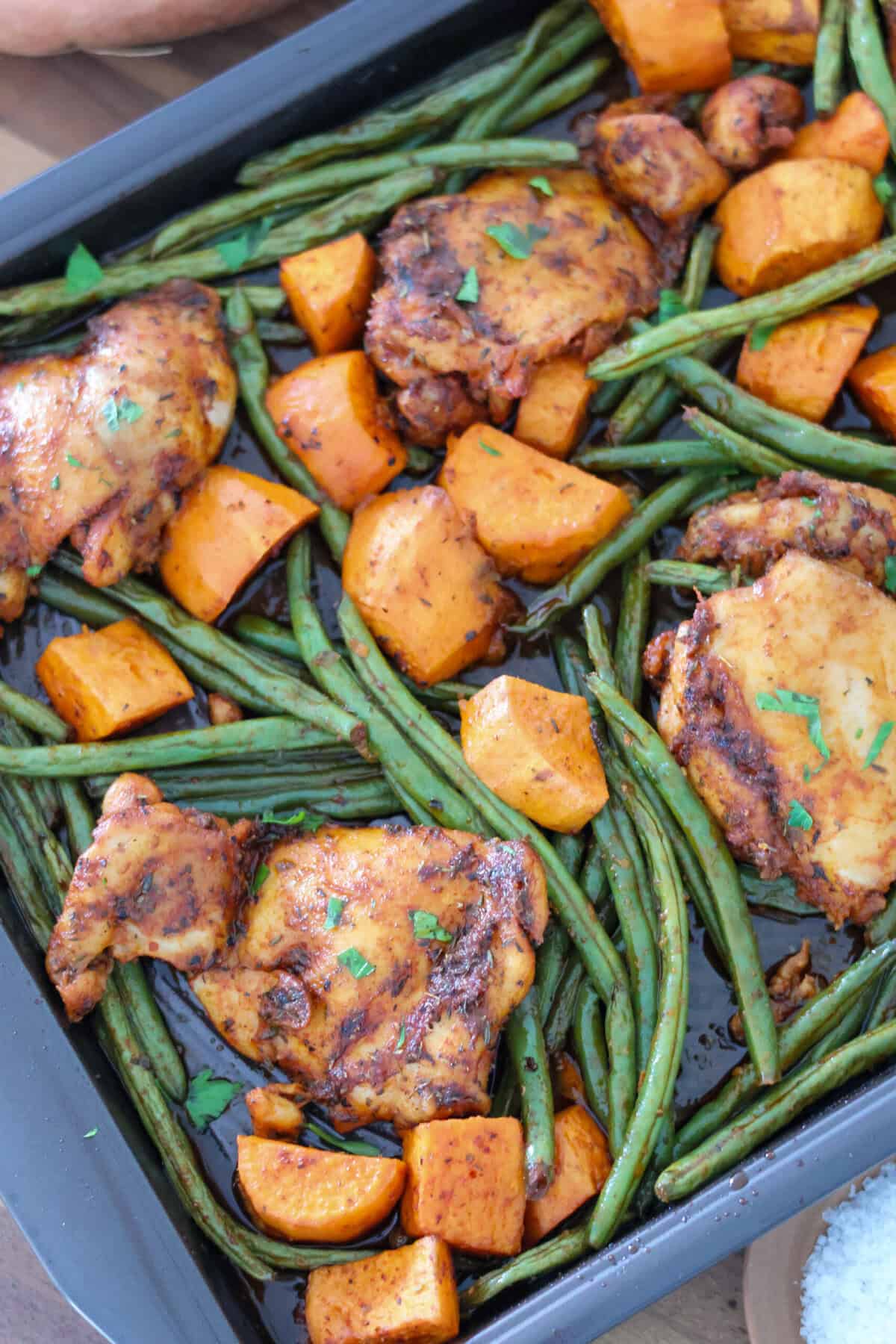A sheet pan of chicken thighs, green beans and sweet potatoes.