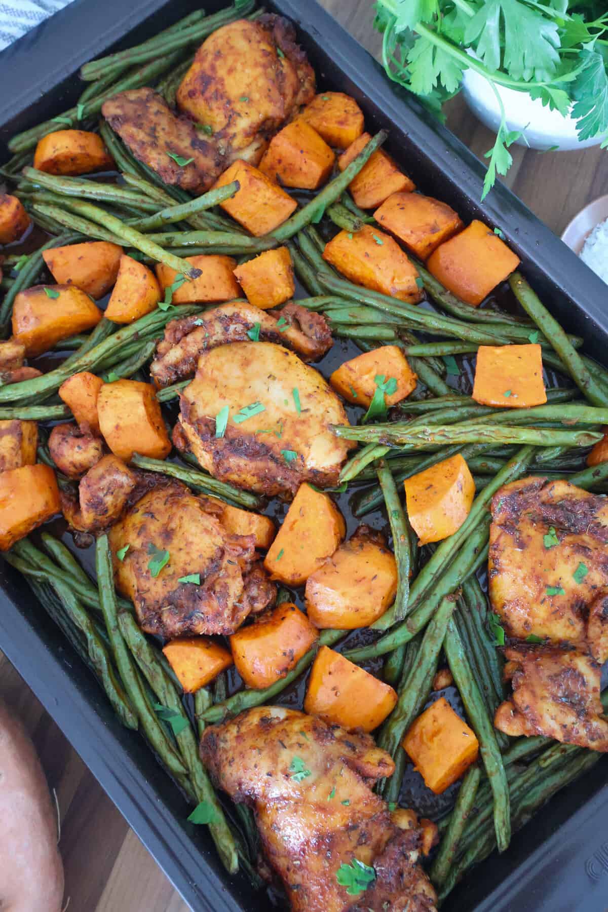 A sheet pan of chicken thighs, green beans and sweet potatoes.