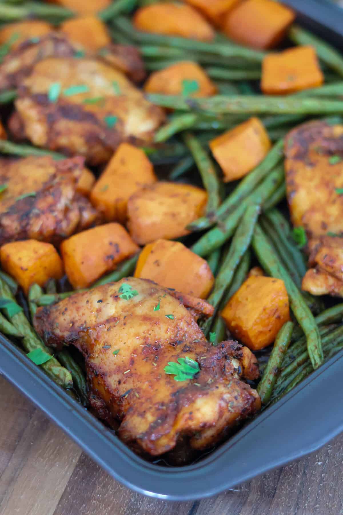 A sheet pan of chicken thighs, green beans and sweet potatoes.