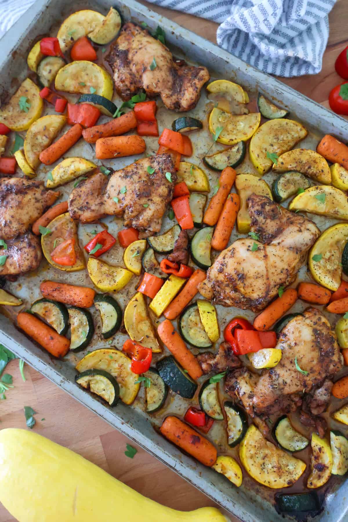 A baking sheet of chicken and carrots and zucchini baked in the oven.