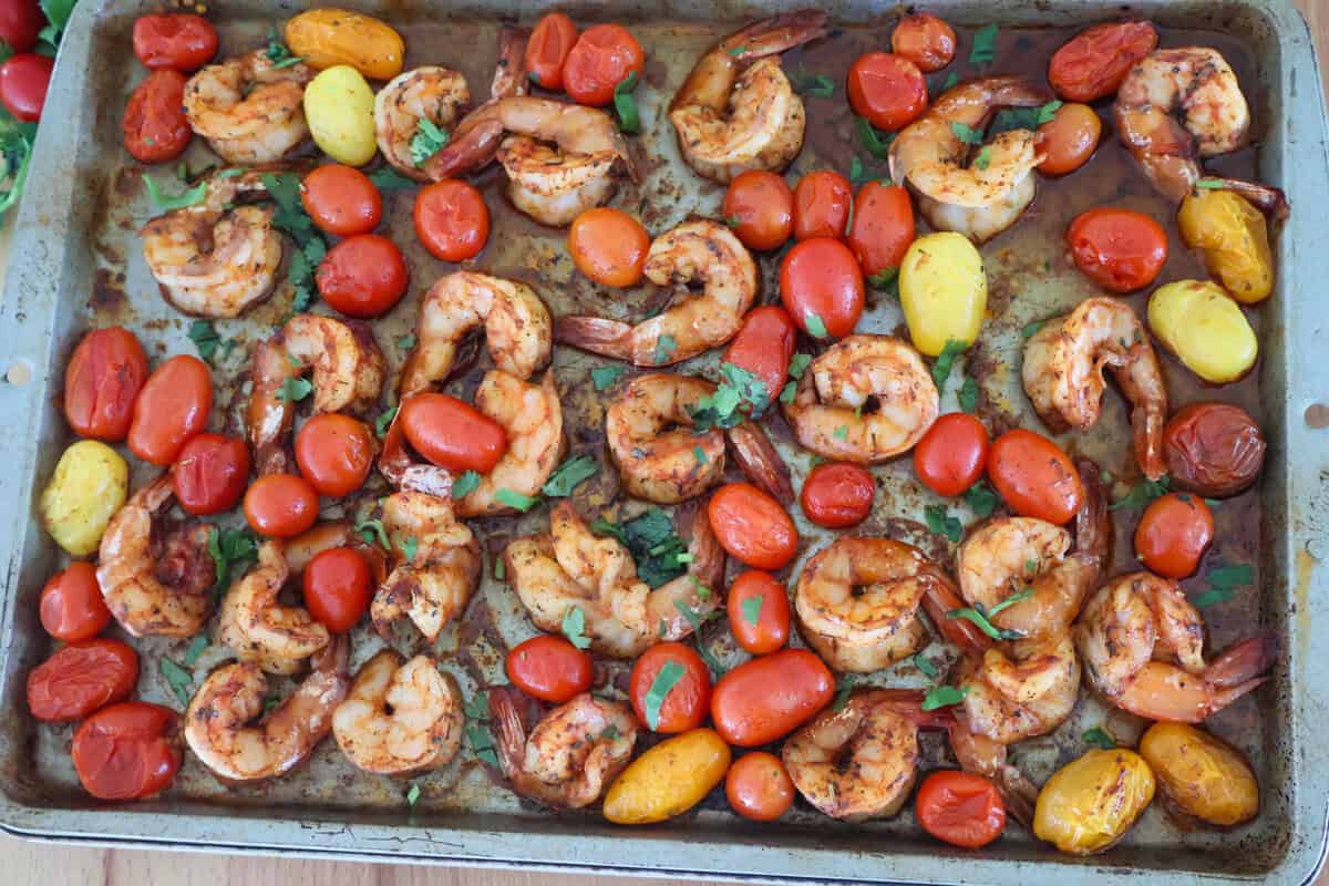 A sheet pan of cooked shrimp and tomatoes.