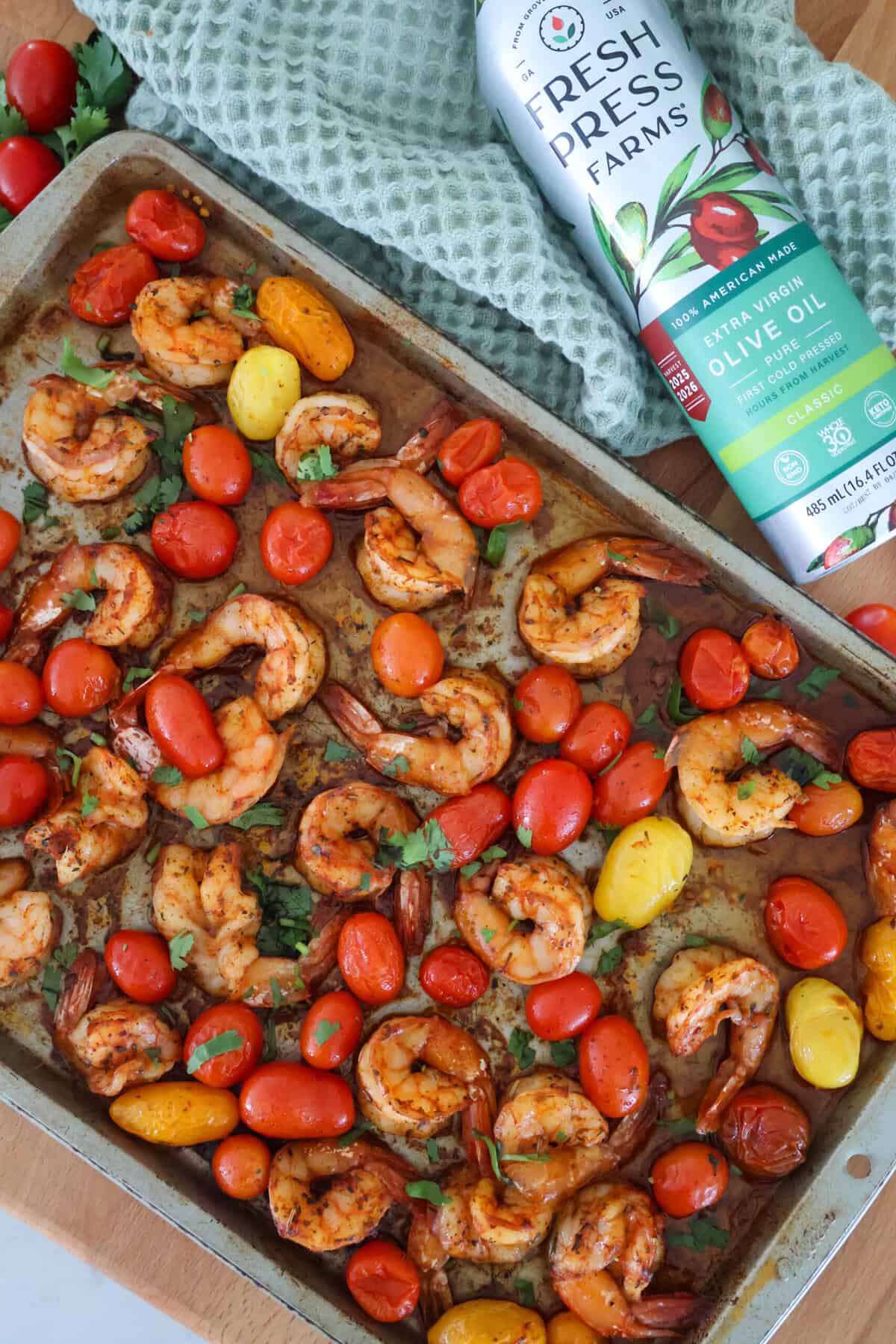 A baking sheet full of cooked shrimp and cherry tomatoes.