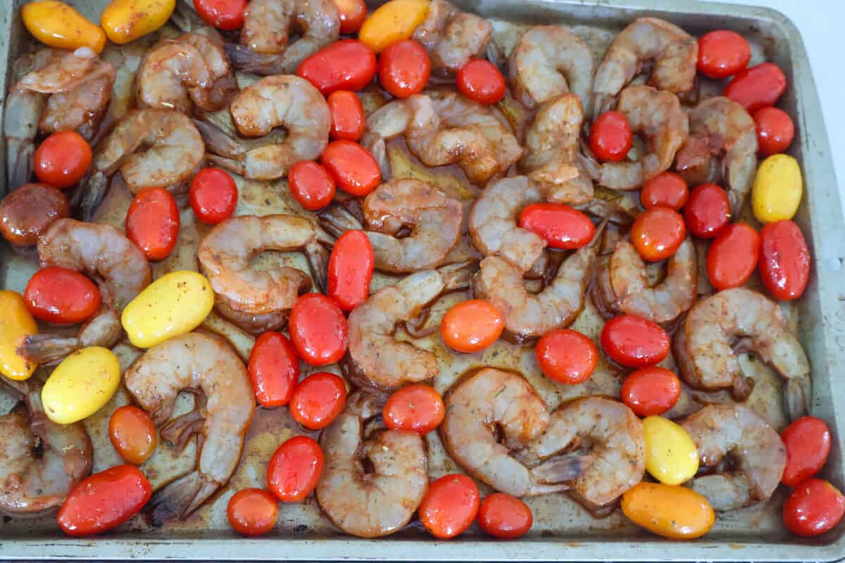 Raw shrimp and tomatoes on a sheet pan ready to go into the oven.