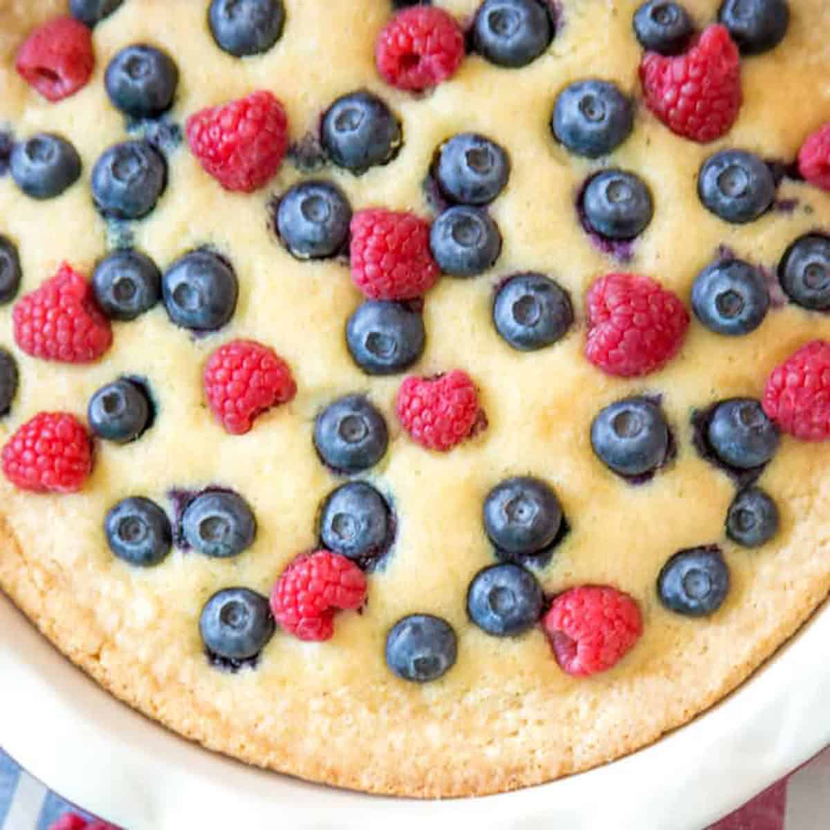 A buttermilk cake topped with blueberries and raspberries.