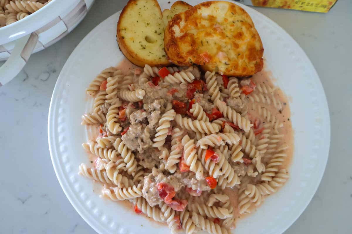 A plate of cream sausage pasta with Texas toast at the top.