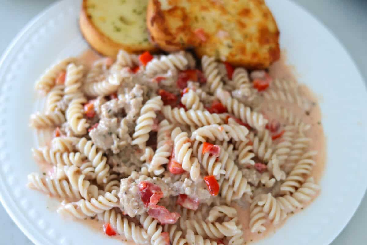 A plate of cream sausage pasta with Texas toast at the top.