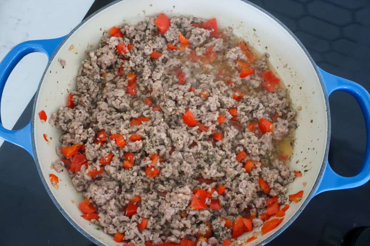 Ground sausage and red peppers cooked in a pan.