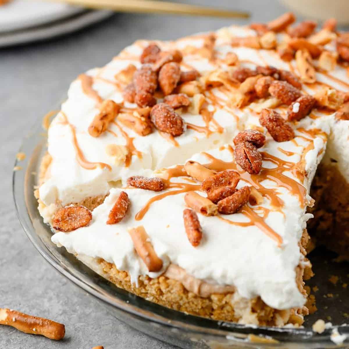 A sliced peanut butter pretzel pie topped with whipped cream.