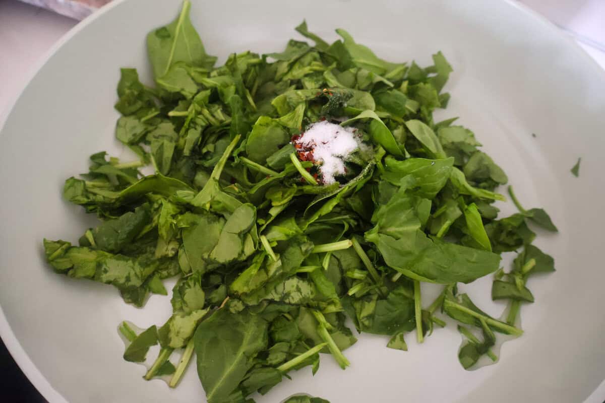A sauce pan of fresh greens being wilted.