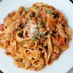 Creamy bolognese sauce and pasta on a white plate.
