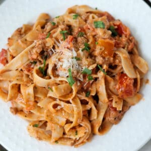 Creamy bolognese sauce and pasta on a white plate.