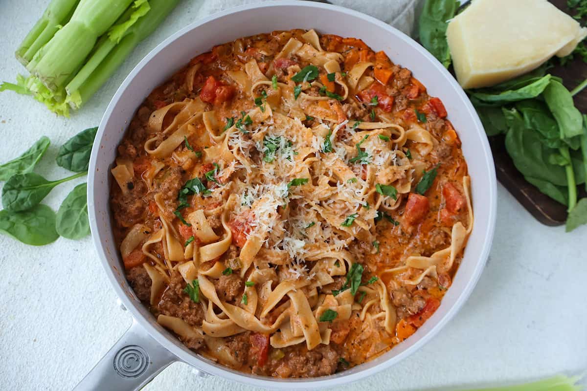 A skillet full of creamy bolognese sauce tossed with pasta.