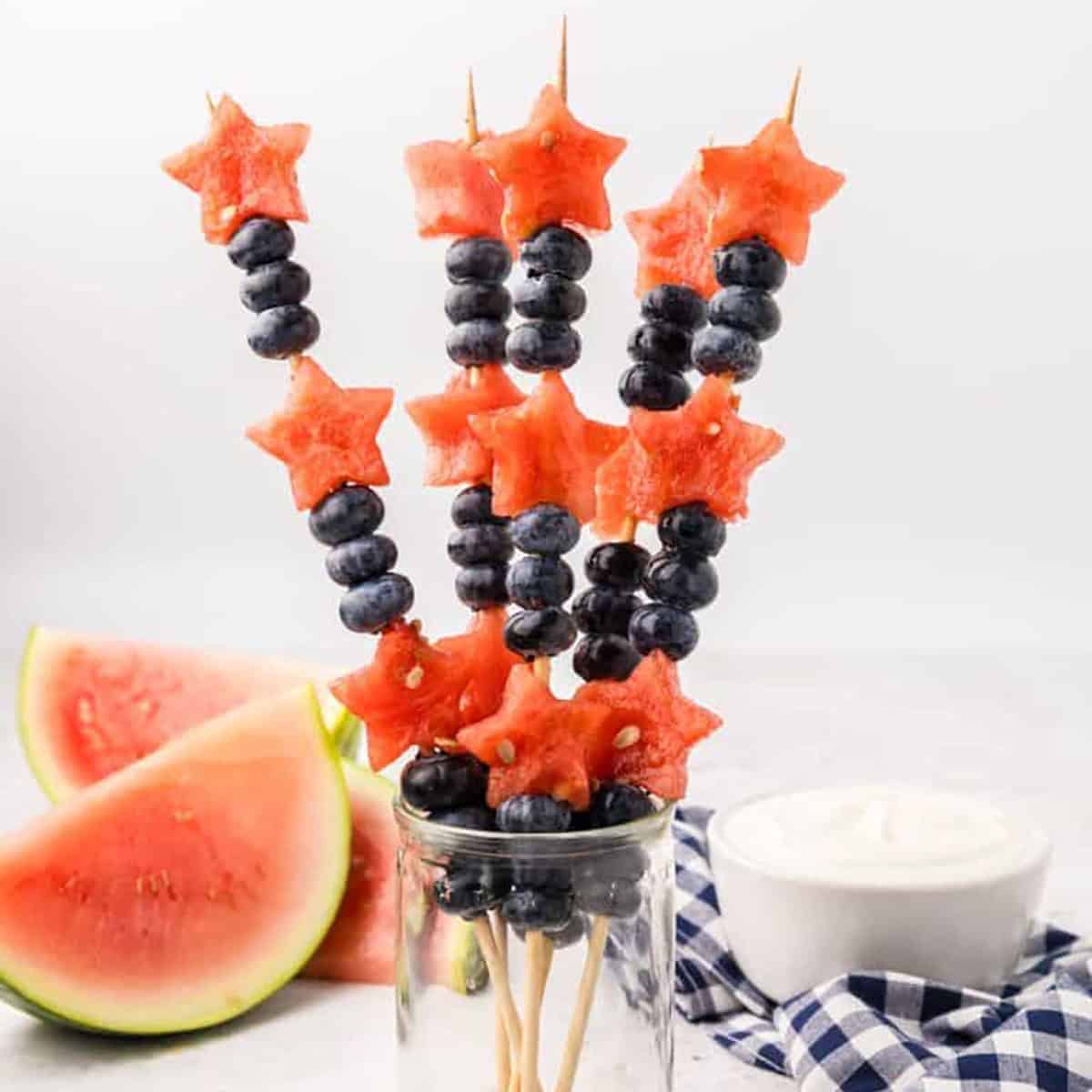 Watermelon and blueberry sparkler kabobs in a glass.