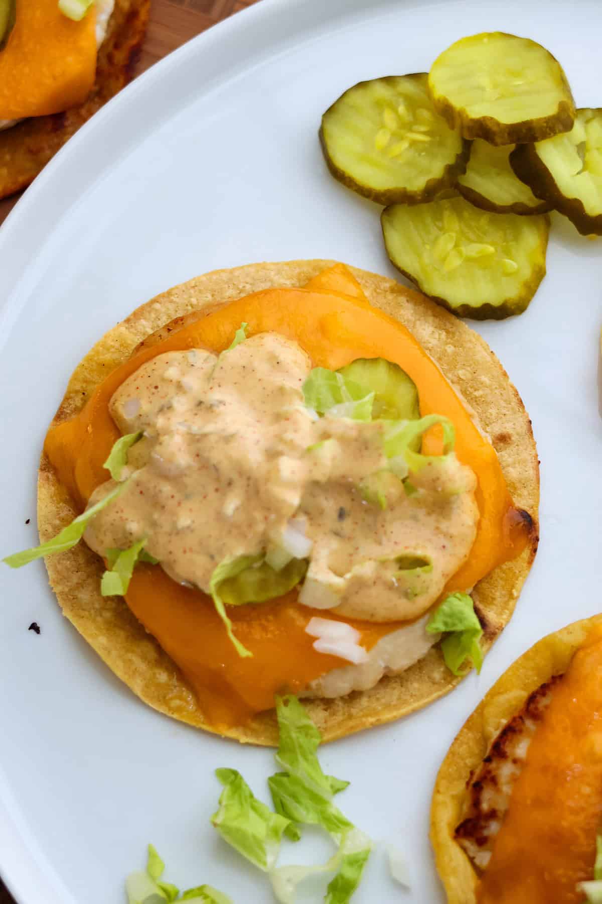 A Big Mac taco with sauce and pickles on a white serving plate.