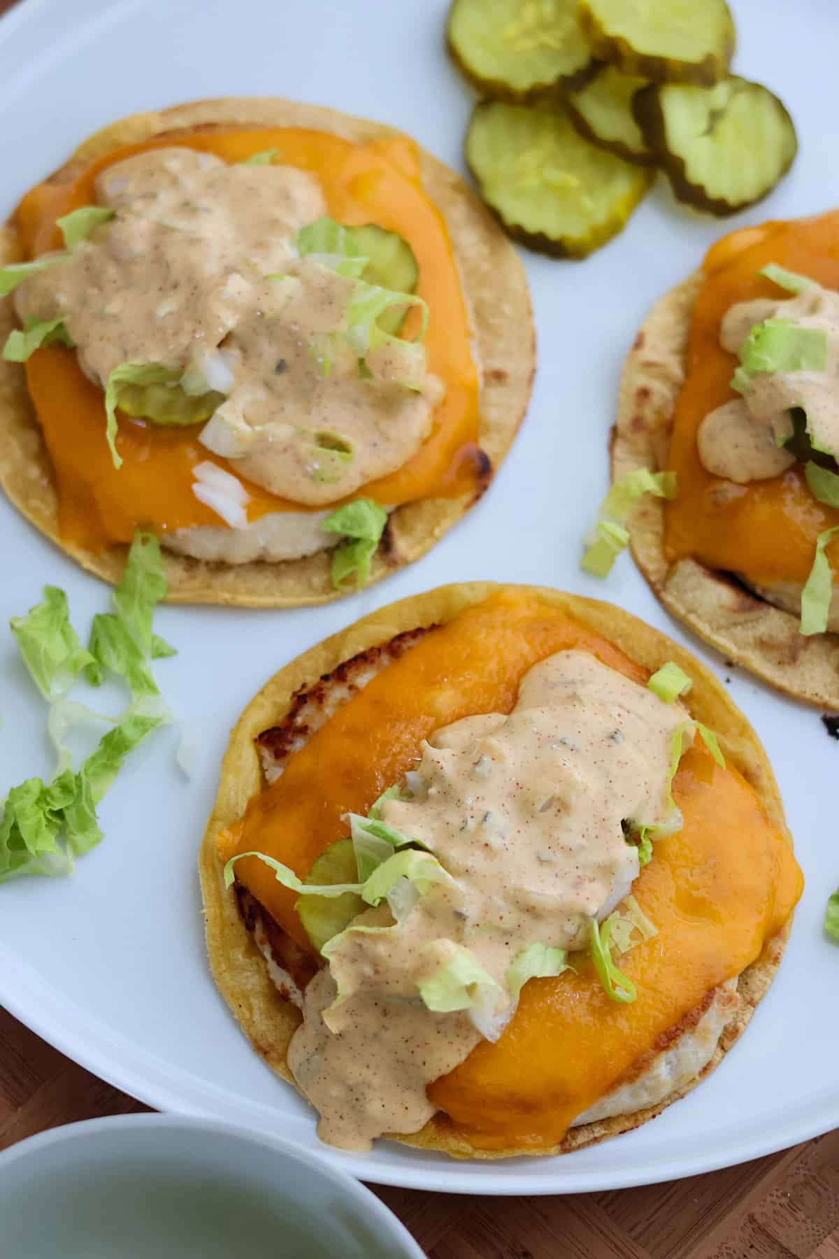 Two chicken smash burger tacos topped with Big Mac sauce on a white plate.