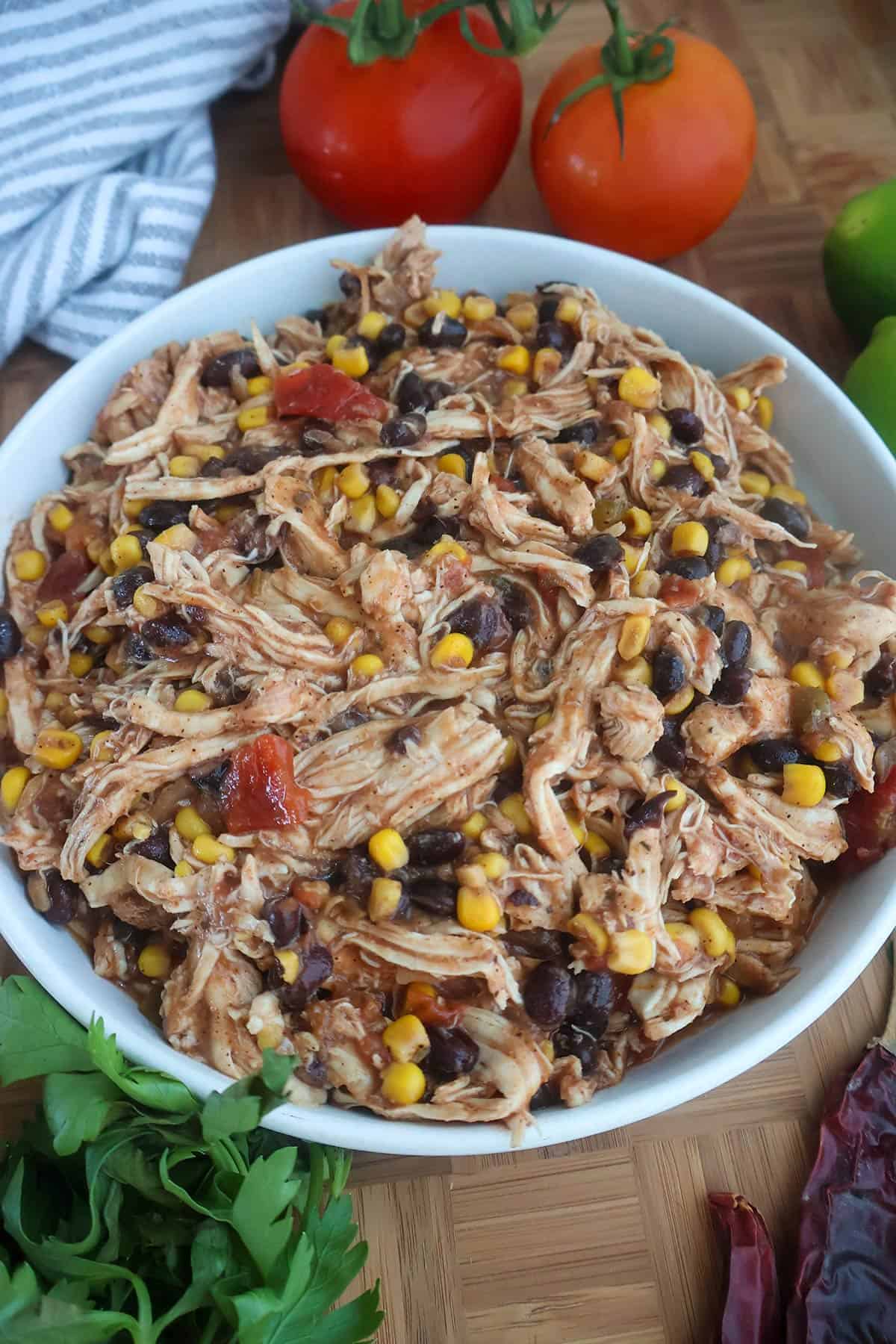 A white bowl filled with a mix of shredded chicken, beans, and corn.