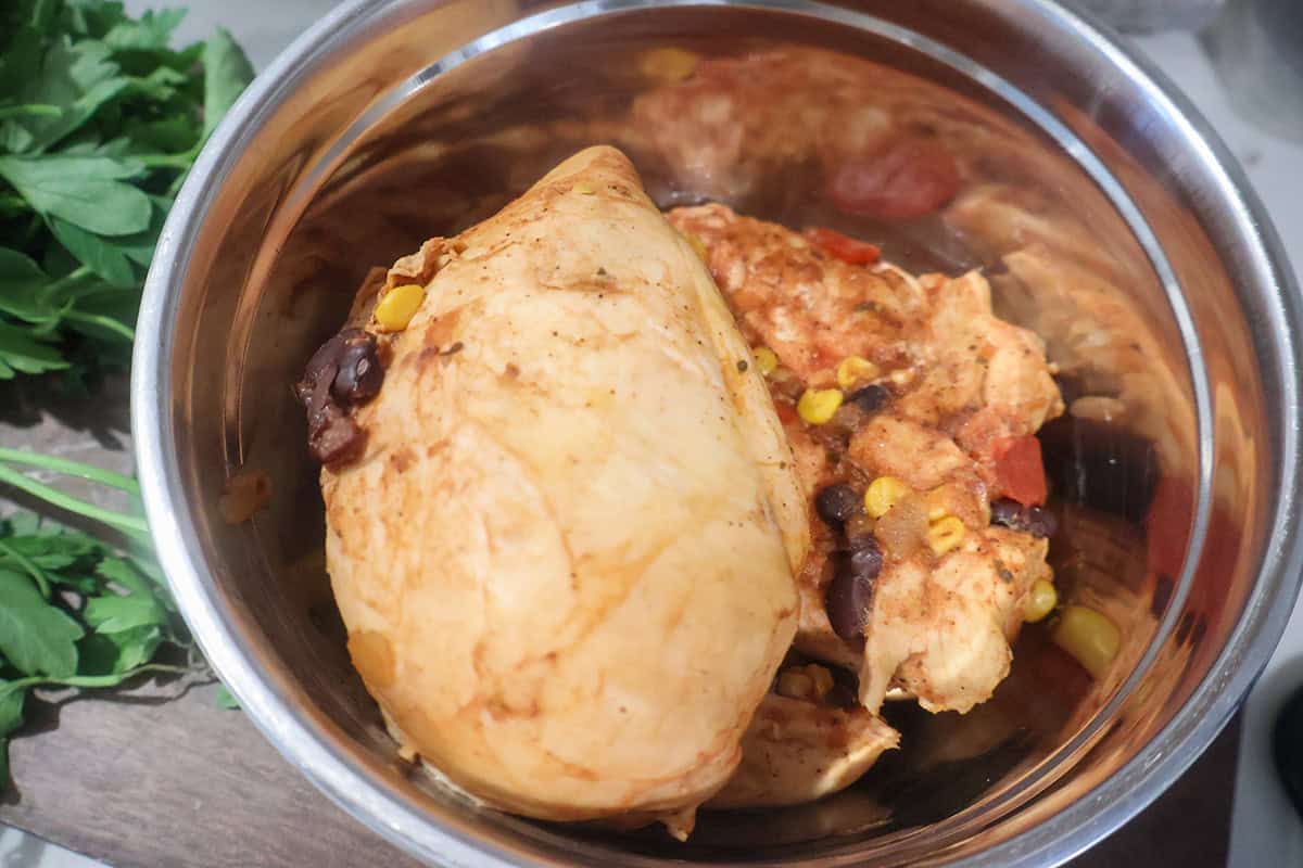 Cooked chicken breasts in a metal bowl.