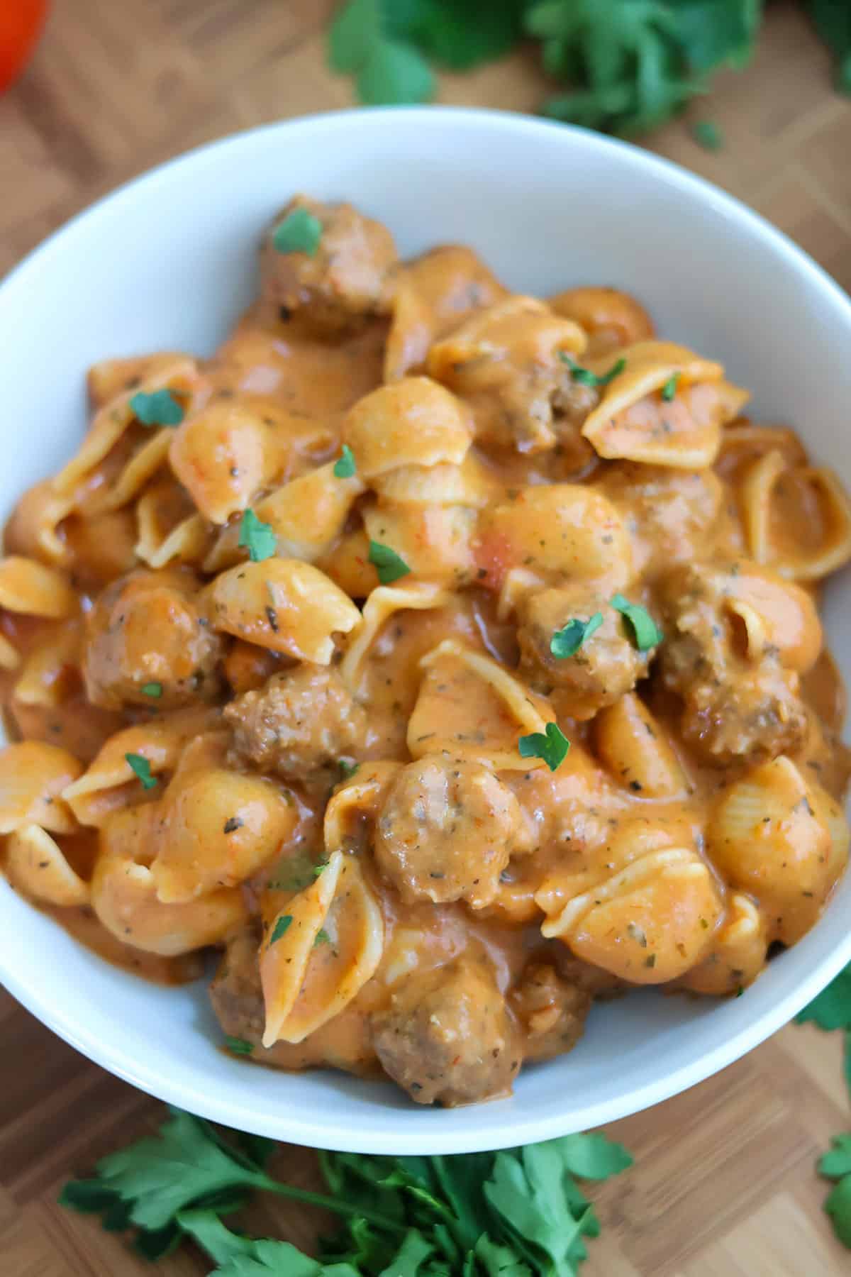 A white bowl full of mini meatball pasta in sauce.