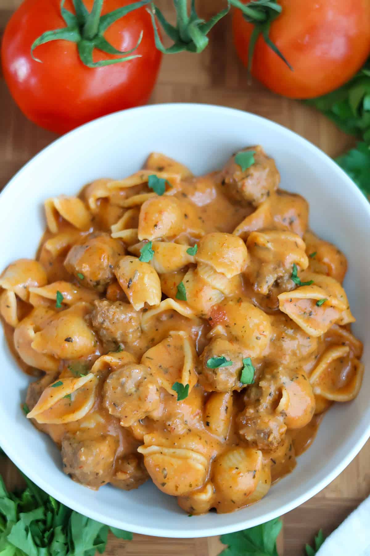 A white bolwful of creamy mini meatballs with pasta.