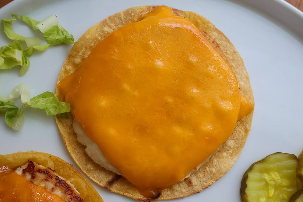 A cheese-topped chicken pattie on a corn tortilla.