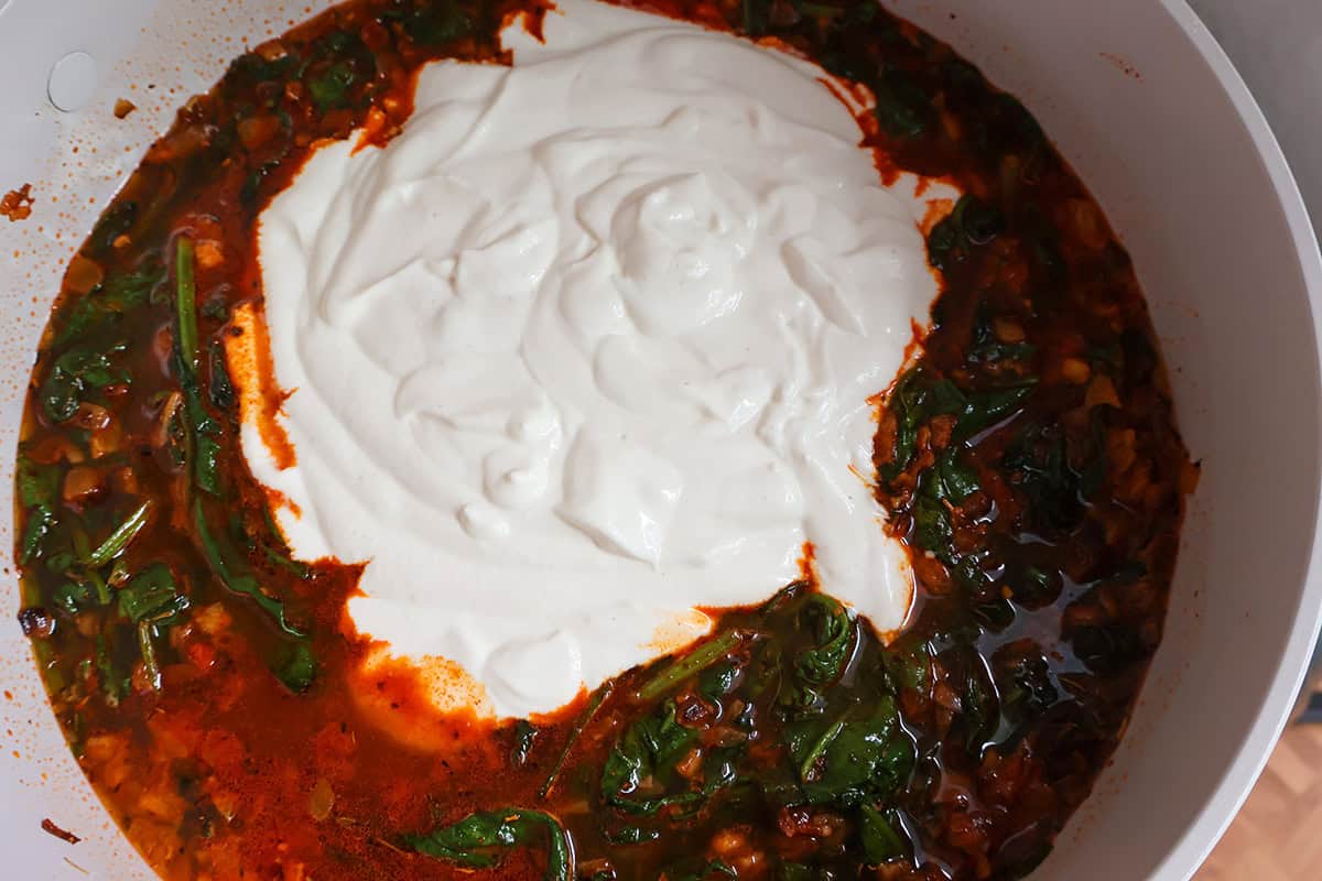 Sauteed spinach, chicken stock, and sour cream in a pan.