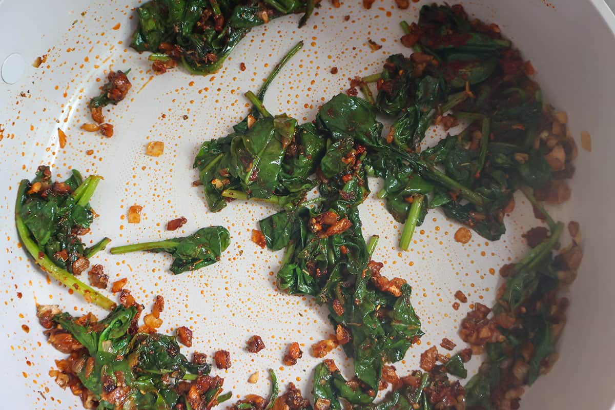 Sauteed spinach and herbs in a skillet.
