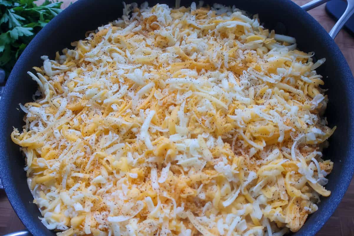 A skillet of mac and cheese covered with more cheese on top.
