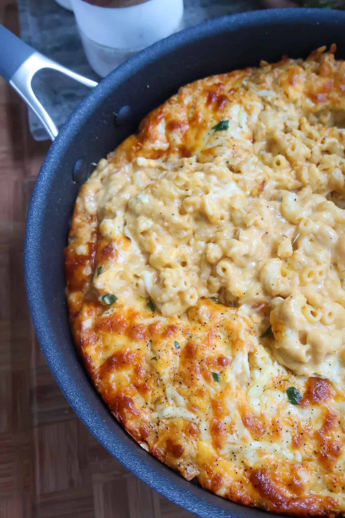A skillet of 5 cheese macaroni and cheese with a brown crust.