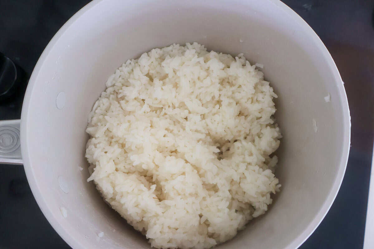 A pot of cooked jasmine rice sitting on the stove.