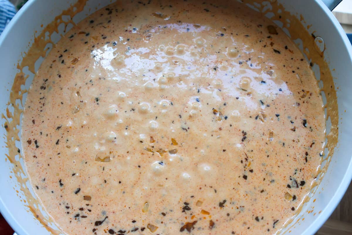 A creamy parmesan and sun-dried tomato sauce simmering on the stove.