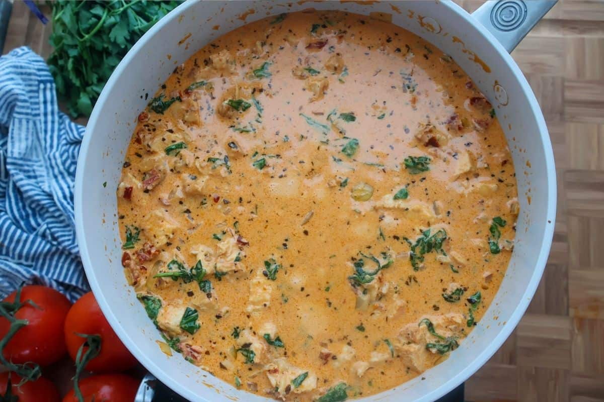 Marry Me Chicken sauce in a skillet on a wood cutting board.