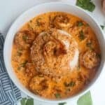 A white bowl of creamy marry me shrimp atop white jasmine rice.