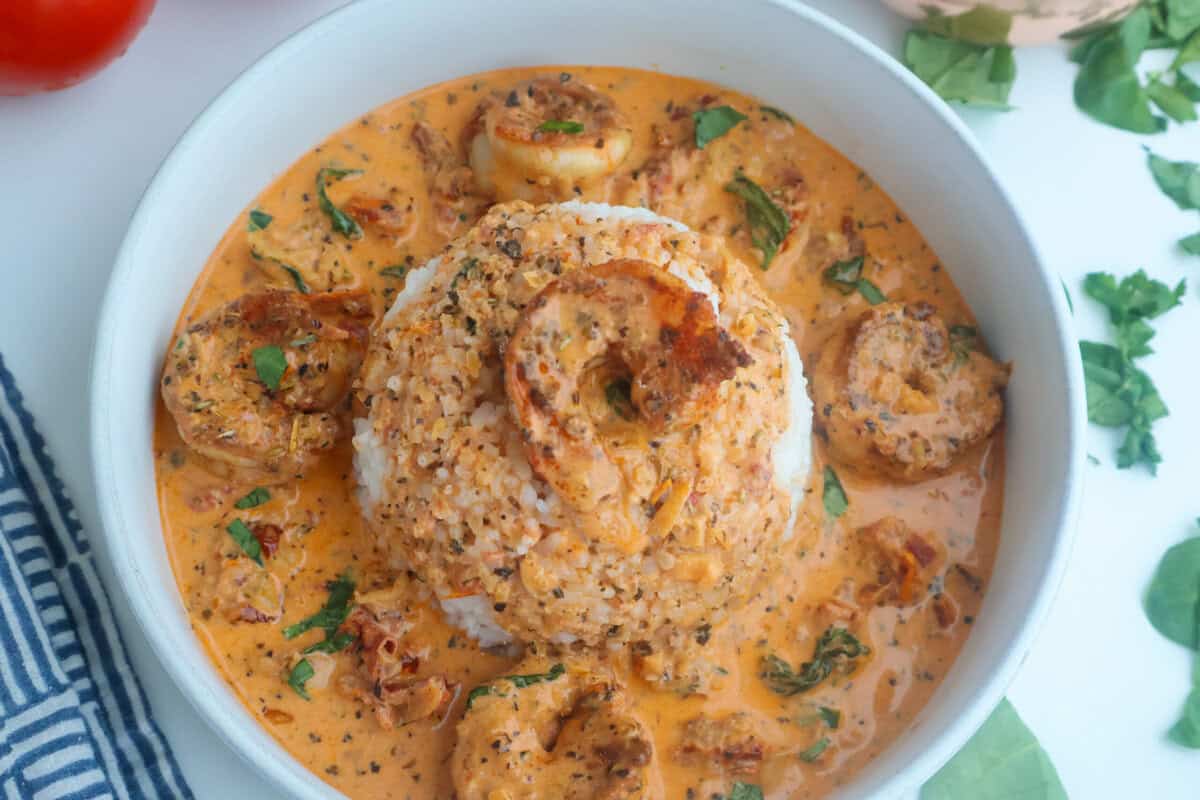 Marry me shrimp and cream sauce poured over white rice in a bowl.