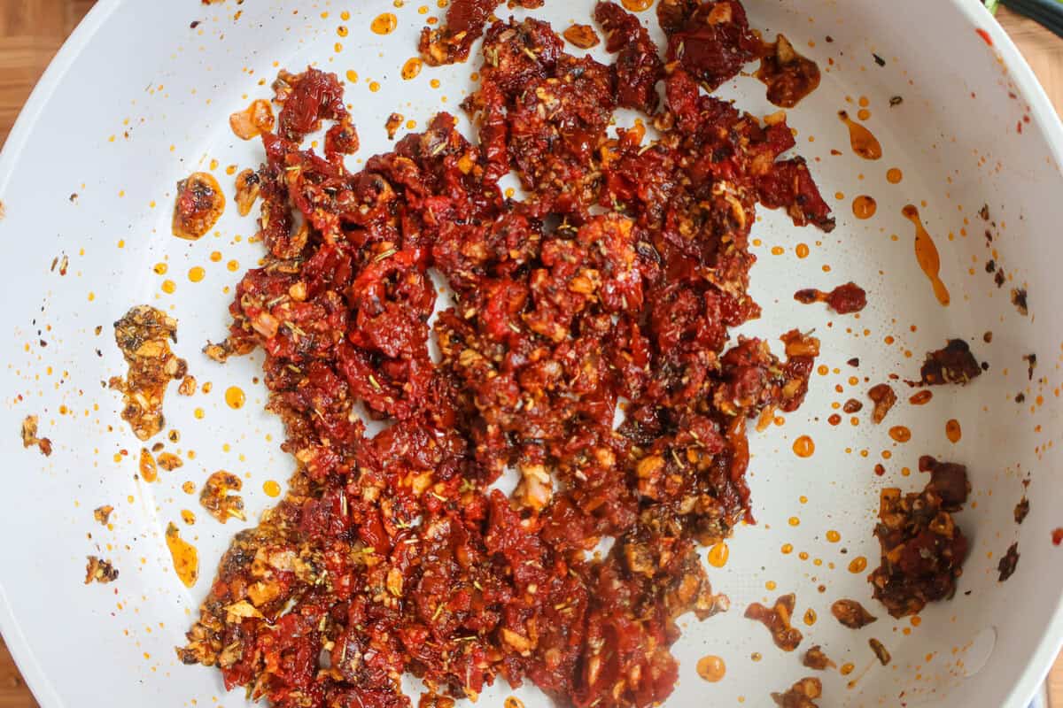 A mix of sun-dried tomatoes and seasoning ready to be deglazed.