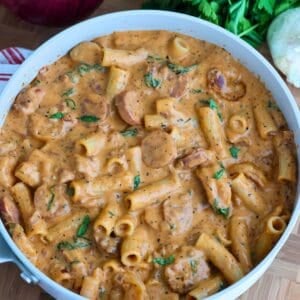 A pan of New Orleans Marry Me Pasta with fresh greens nearby.