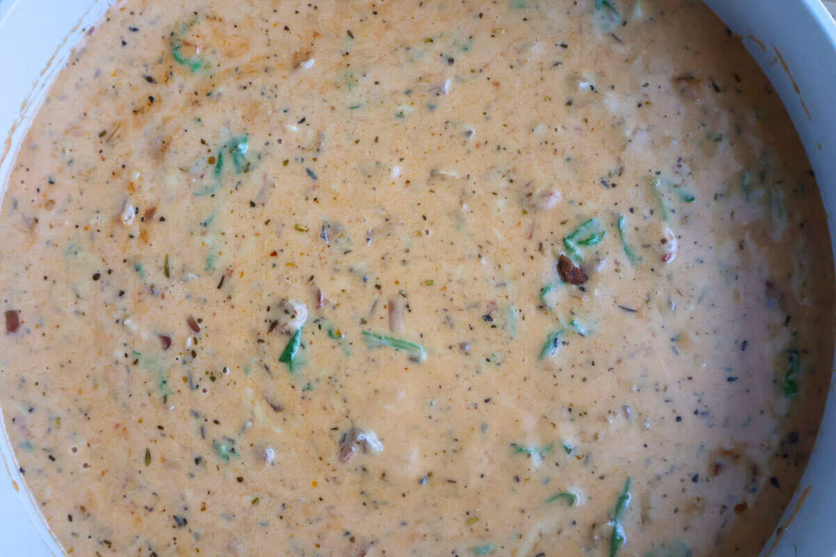 A parmesan cream sauce cooking in a white skillet..