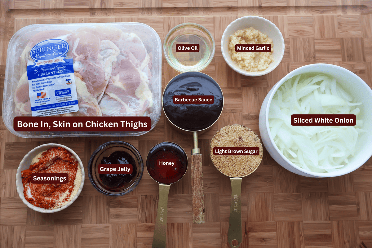 Labeled ingredients for baked BBQ chicken thighs: chicken thighs, olive oil, minced garlic, barbecue sauce, sliced white onion, seasonings, grape jelly, honey, and light brown sugar