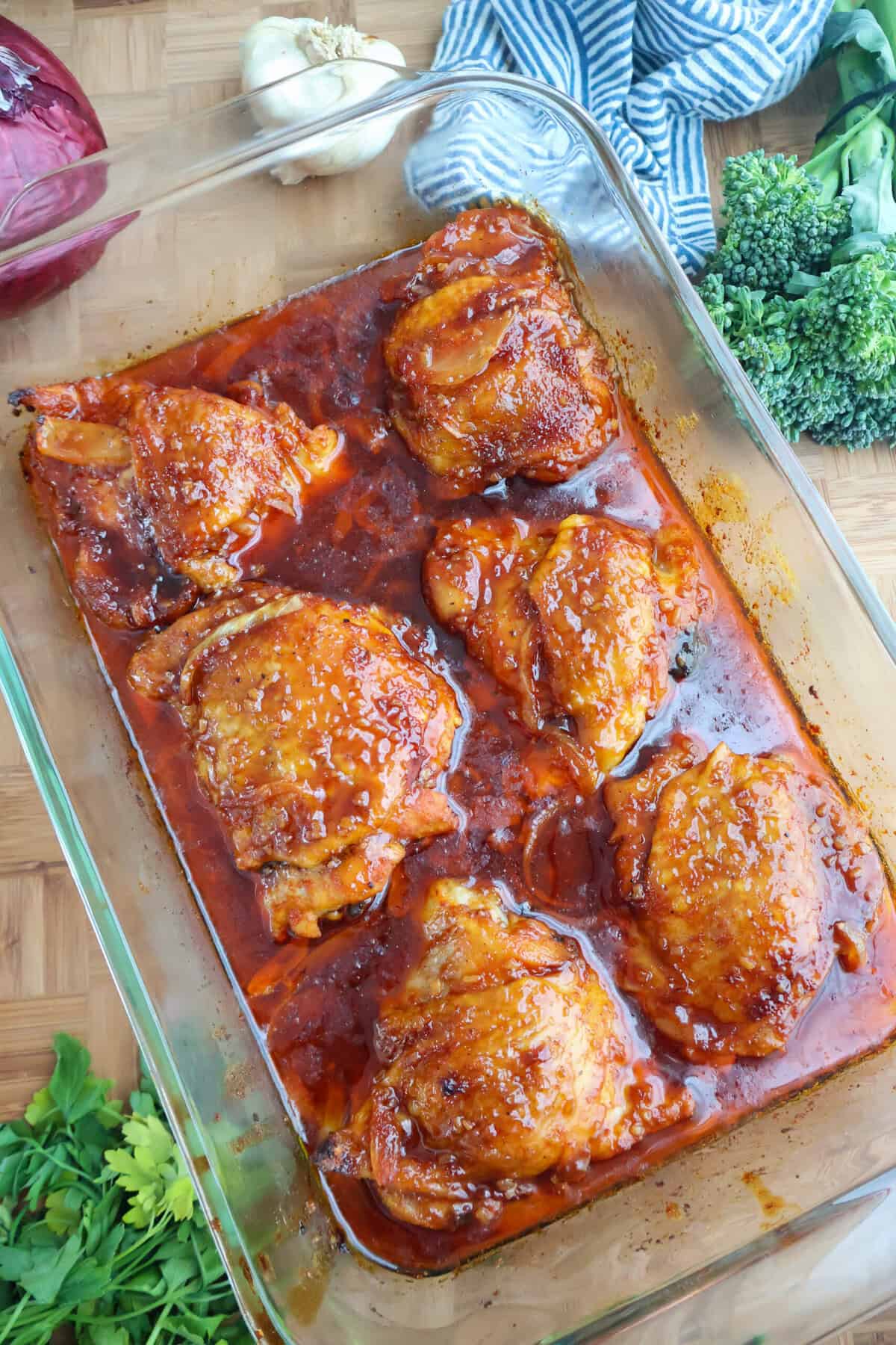 Baked BBQ chicken thighs glazed in barbecue sauce in a glass baking dish