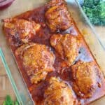 Baked BBQ chicken thighs glazed in barbecue sauce in a square glass baking dish